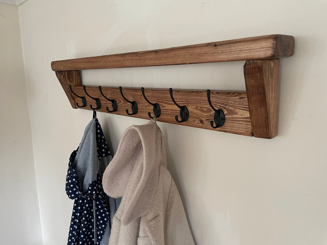 Rustic wooden coat rack with black hooks holding coats and bags